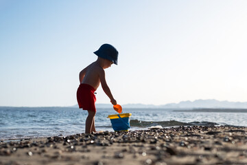 Boy kid in red shorts on the summer beach