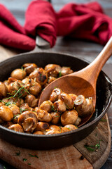 Fried champignons in a frying pan on a dark wooden background. Cooked mushrooms close-up.