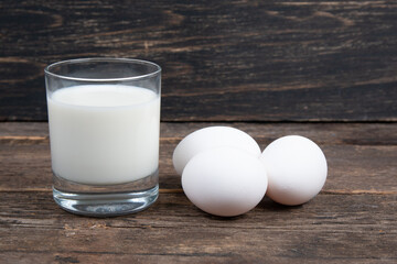 glass of milk and chicken eggs on a wooden table