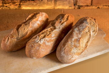 Large rustic loaves of freshly baked sourdough bread on wooden cutting board
