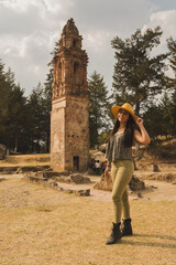 Adventurous girl with yellow hat posing for photo in the ruins of an old church in the middle of the forest