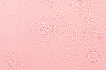 de-focused. Closeup of pink transparent clear calm water surface texture with ripples, splashes and bubbles. Trendy abstract summer nature background. Coral colored waves in sunlight.