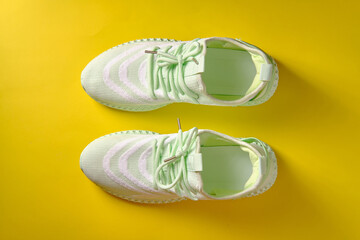Women's green sneakers on a yellow background, top view, place for an inscription