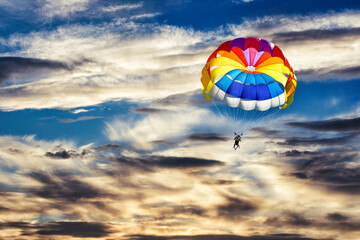 A woman is gliding with a parachute on the background of sunset.