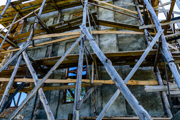 Wooden scaffolding near the old building. Ancient building restoration