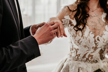 womans hands with gold and silver rings on fingers groom putting on ring on wedding day bride