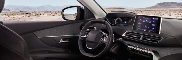 Cockpit of a modern SUV with a view of the desert and mountains. In the mirror you can see the road on which it stands.