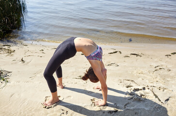 woman performing asanas and enjoying life on the sea. Yoga on the beach