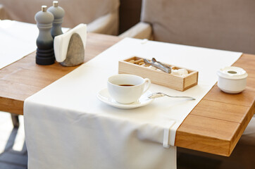 Hot coffee in a cup on wooden table. Modern design interior, restaurant blur background with bokeh image