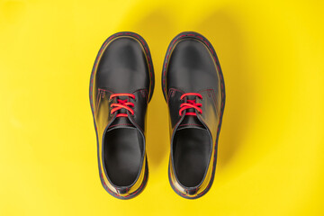 Stylish black leather shoes on yellow background, flat lay, top view