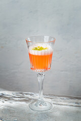 Orange cocktail with egg white and pistachio ont top served on ice block