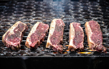 Raw beef steak with black pepper on grill with steam coming out. Selective focus barbecue concept.