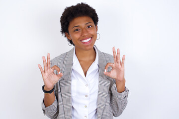 African American businesswoman with curly bushy hair wears  formal clothes over white background showing both hands with fingers in OK sign. Approval or recommending concept