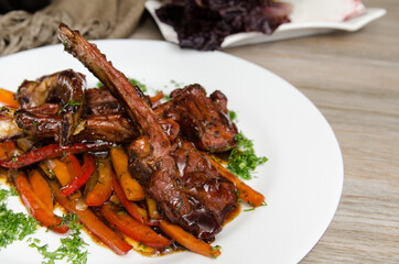 grilled lamb ribs with vegetables on a white plate close up