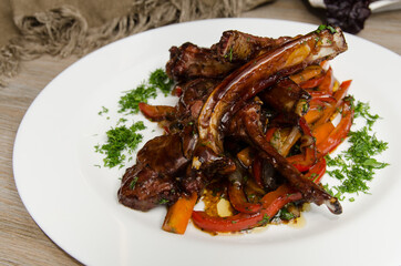 grilled lamb ribs with vegetables on a white plate close up 