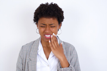 Fototapeta na wymiar African American businesswoman with curly bushy hair wears formal clothes over white background touching mouth with hand with painful expression because of toothache or dental illness on teeth.