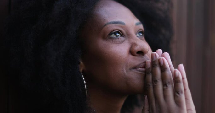 African woman feeling HOPE and GRACE. Person praying to GOD looking at sky