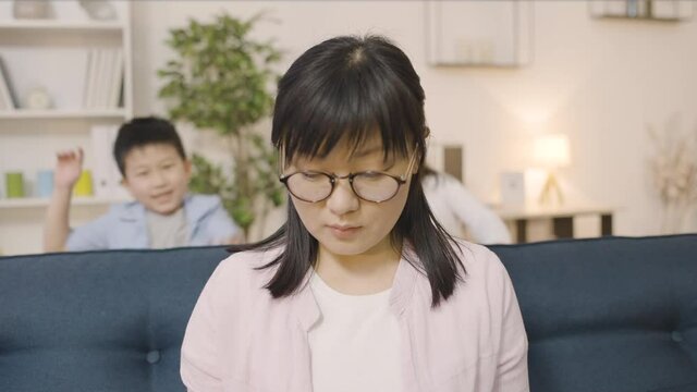 Distressed asian mother working home, suffering headache from noisy children