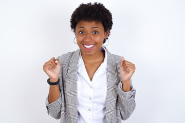 African American businesswoman with curly bushy hair wears  formal clothes over white background celebrating surprised and amazed for success with arms raised and open eyes. Winner concept.