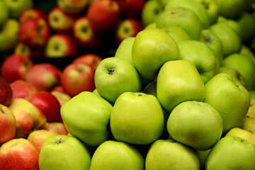 The green and red apples are stacked neatly in a pile
