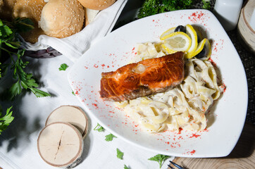 grilled salmon steak with pasta on a white plate