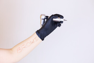 A girl's hand in a black glove holding a tattoo machine