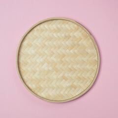 Round empty wicker straw basket on a pink background. View from above. Decorative interior items.