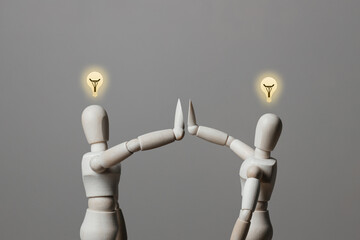 Wooden dummy gives a high five for a good idea. A light bulb above your head. Concept of a great idea. Copy space