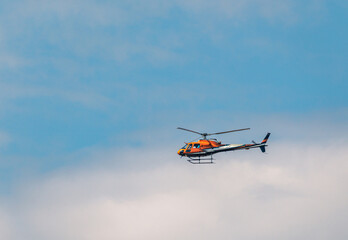 Fototapeta na wymiar Orange Helicopter flying in the blue sky