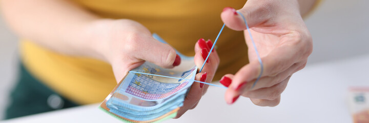 Woman binding euro cash with rubber band closeup