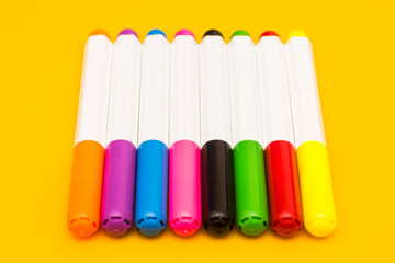 Naklejka premium Multicolored markers in a row on a yellow background. Children's drawing