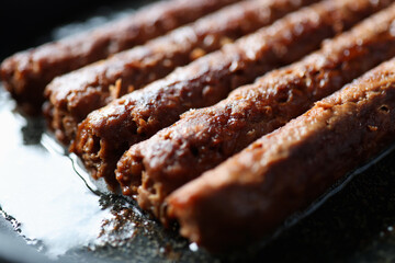 Fried sausages lying in frying pan closeup