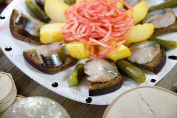 salted herring is an appetizer for vodka on the Christmas table with potatoes and pickles