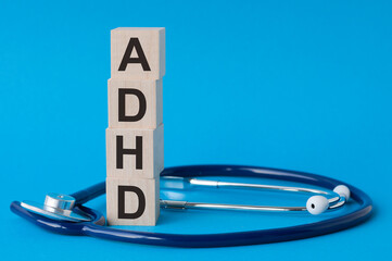 adhd letters word written on wooden blocks and stethoscope on light blue background
