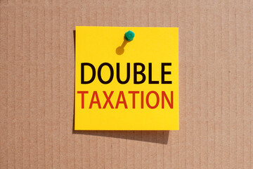 words double taxation written on yellow square paper and pinned on craft paperboard