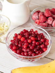 Red wild frozen cranberries with raspberries and banana, healthy ingredients for a morning breakfast smoothie. Organic natural fruits full of antioxidants, vitamis, minerals for clean eating diet.