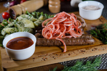 grilled sausages on a wooden board with chopped vegetables and onion with paprika 