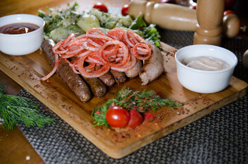 grilled sausages on a wooden board with chopped vegetables and onion with paprika 