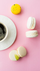 Fototapeta na wymiar Various macaroon cakes, white cup with coffee on pink background. Image with selective focus