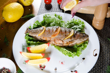 fried fish stuffed with lemon slices on a white plate with a lettuce leaf
