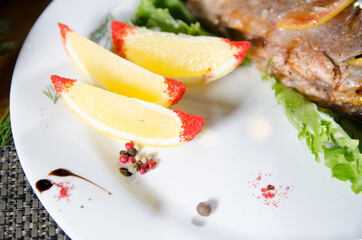 three slices of lemon with paprika on a white plate near the fried fish