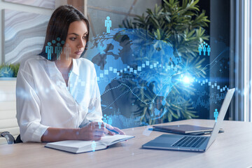Attractive businesswoman in white shirt at workplace working with laptop to hire new employees for international business consulting. HR, social media hologram icons over office background