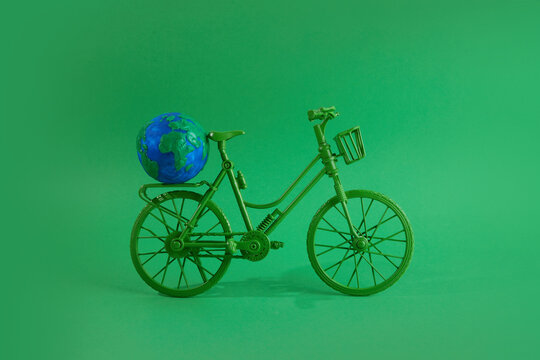 World bicycle day concept. Green bicykle with globe on green background. 3 june.