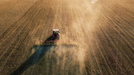 farm tractor with cultivator works the field aerial video