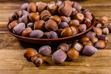 Plate with pile of hazelnuts on a wooden table