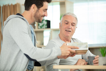 Fototapeta premium senior father with adult son relaxing on sofa at home