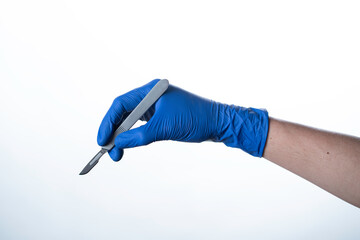 doctor wearing blue gloves holding scalpel
