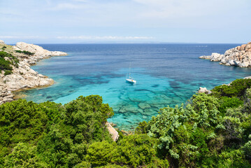 Blaue Bucht mit Segelboot bei Capo Testa auf Sardinien am Mittelmeer mit Blick auf Korsika