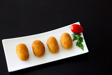 Homemade traditional Spanish croquettes or croquetas on a black background