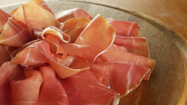 Cured raw ham, spinning. Slices of prosciutto crudo, Italian food. Pork dried ham. Antipasto, cold cuts. 4k video.